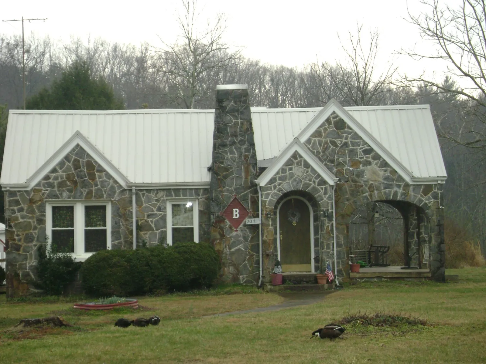 White metal roof on a stone cottage with steep gables in Louisville