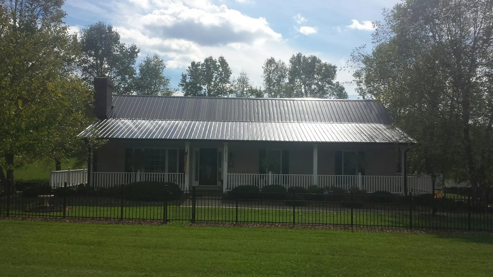Gray metal roof on a brick ranch with a full width front porch — Gutter Guard Installation work by our crew in Louisville